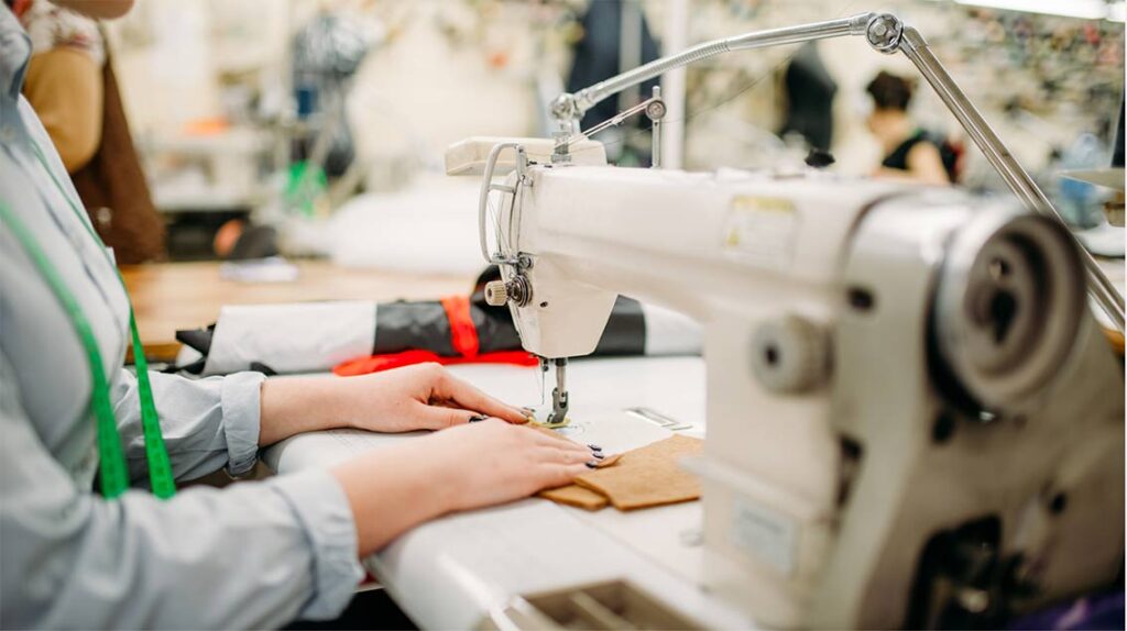 Fashion designer reviewing garment samples with a clothing manufacturer in a production facility. How to Find a Garment Manufacturer 