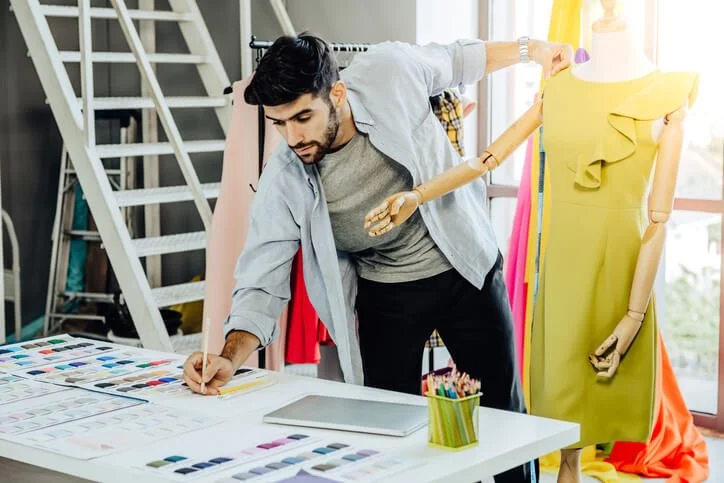 Apparel designer sketching clothing designs and selecting fabrics, illustrating what is an apparel designer in 2025.